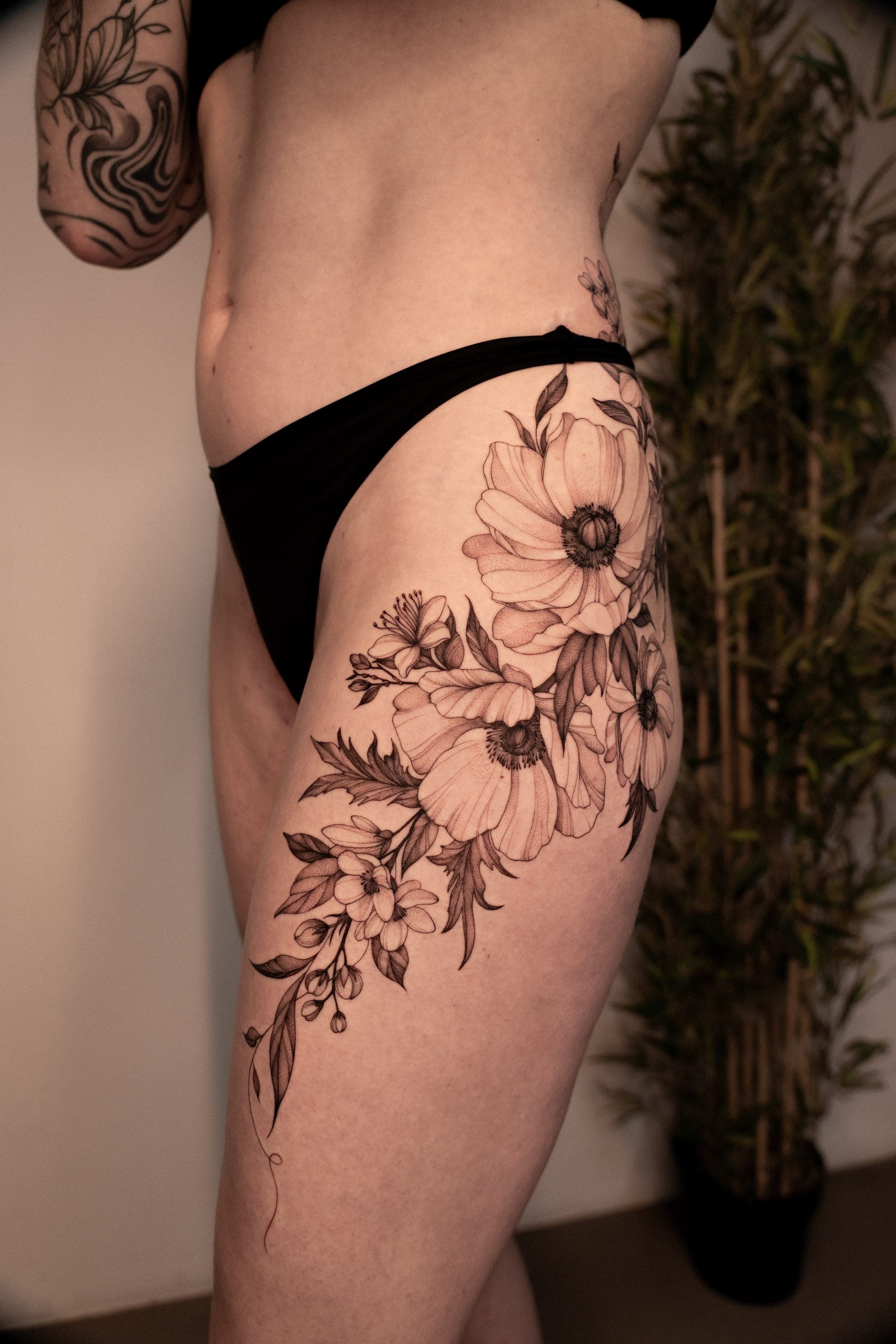 Black and grey botanical flowers on hip tattoo
