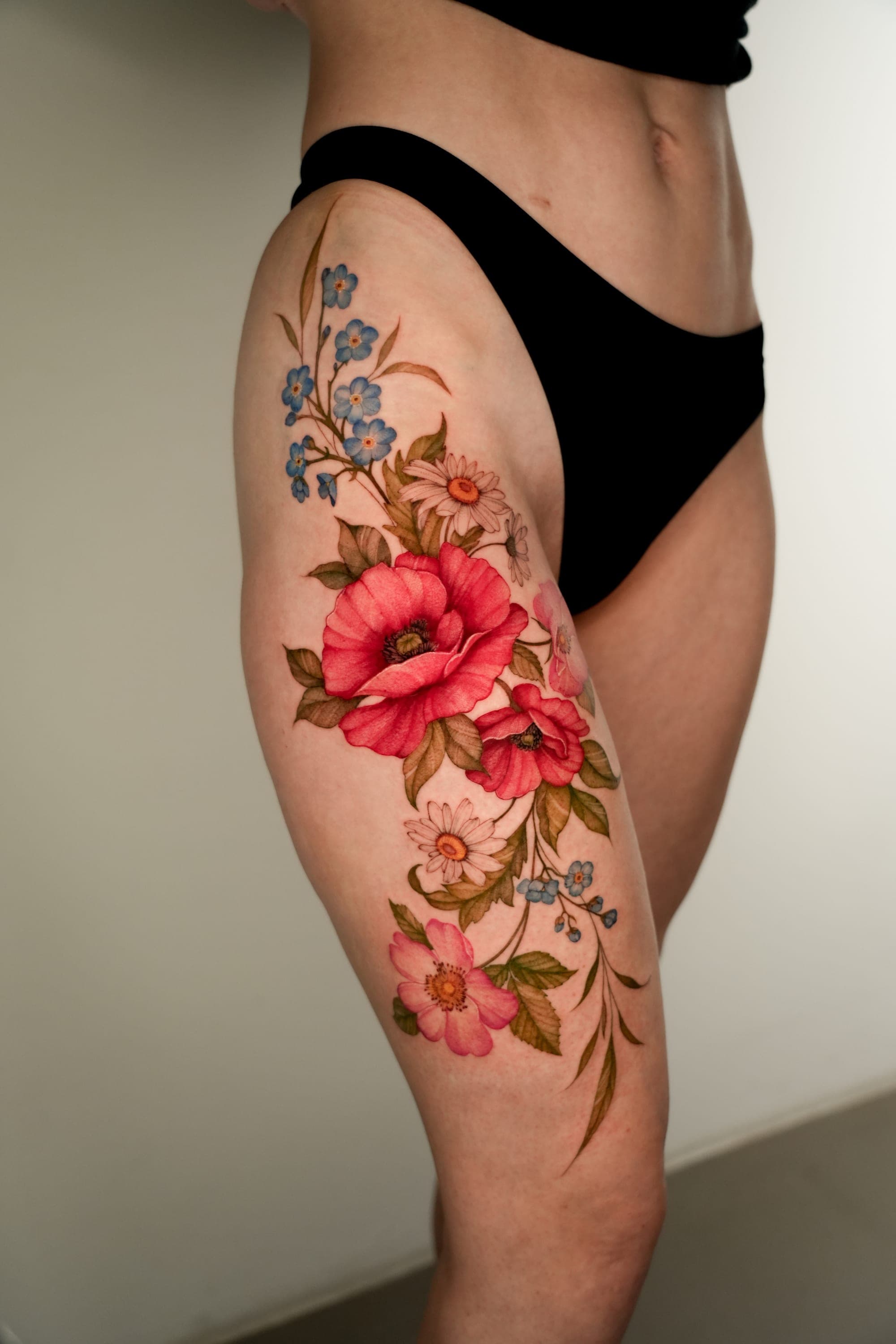 Poppy, daisy and forget-me-not hip tattoo