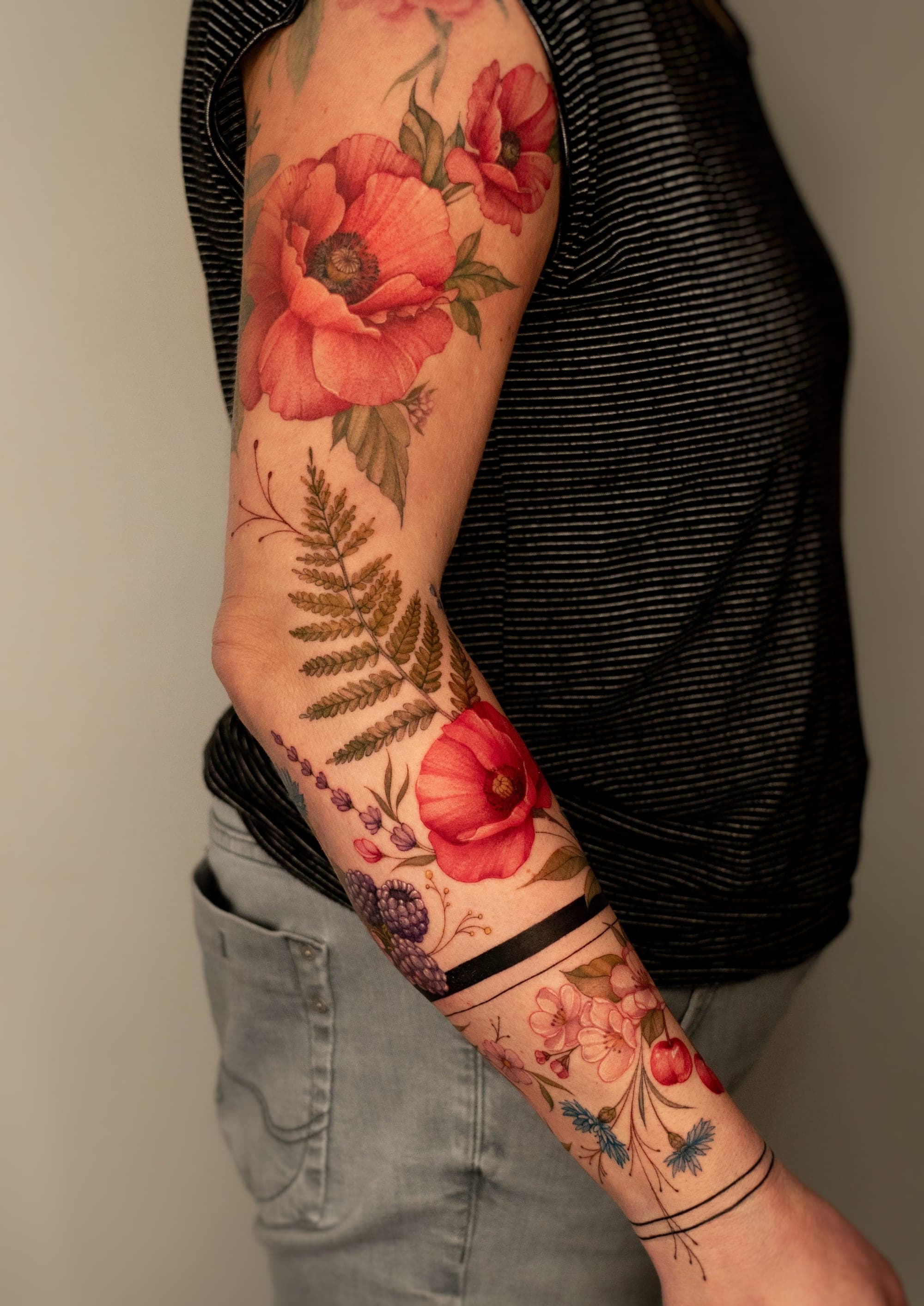 Fern and poppy colorful botanical sleeve tattoo